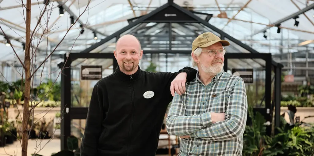 Two customers from Schrader Gartneri inside a Norwegian greenhouse with a commercial heat pump system for efficient climate control.