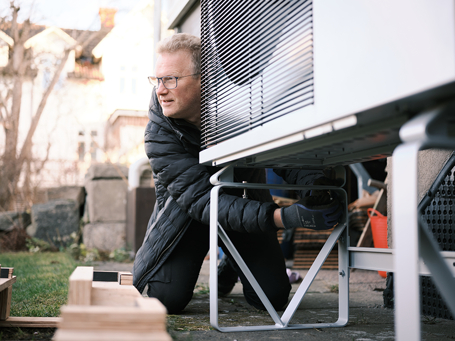 Man installing an outdoor unit outside a house.